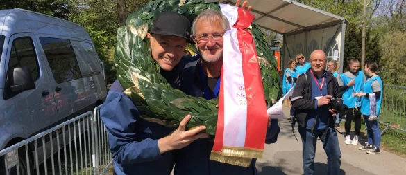 Da war die TSVE-Welt noch in Ordnung: Orgateam-Mitglieder Matthäus Gruben (l.) und Rudi Ostermann erlauben sich im Zielbereich einen Spaß mit dem Kranz während sie auf die schnellsten Läufer und Läuferinnen warten. - © Stephanie Fust