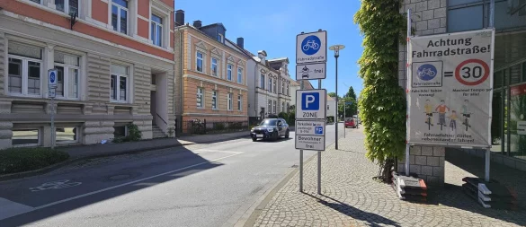 An der Freiligrathstraße in Detmold steht noch ein Transparent, was übersichtlich die Regeln in einer Fahrradstraße erklärt. Baulich ist an der Straße allerdings nicht viel verändert worden. Ein paar Parkplätze wurden in einen "Vorbeifahr-Streifen" für Radler umgewandelt und kurz vor der Ampel ist eine große Haltezone für Fahrradfahrer auf den Asphalt gesprüht worden. - © Jost Wolf