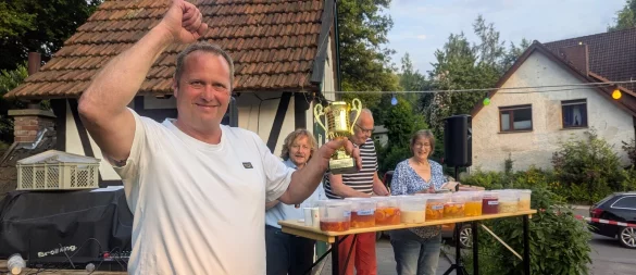 Er ist Bavenhausens neuer Bowle-König: Mario Schleef mit Wanderpokal. Im Hintergrund von links die Jury: Thorsten Rosenau, Dieter Hartwig und Iris Schön. - © Heimatverein Bavenhausen