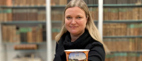 Stadtarchivarin Sonja Beinlich zeigt eine Souvenirtasse aus den 1940er Jahren, auf der das Kurhaus nach dem Anbau der runden Terrasse zur Kurparkseite abgebildet ist. - © Stadtarchiv Bad Salzuflen