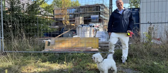 Dr. Johann Malcher steht mit Hund vor der Festhalle, die derzeit saniert wird. - © Sven Kienscherf
