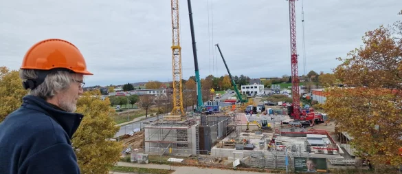 Matthias Rabe schaut vom Dach des Stadtwerke-Gebäudes am Liemer Weg auf die Baustelle auf der anderen Straßenseite. Im unteren Bereich ensteht das Anlagengebäude, weiter oben ist schon das runde Fundament (rot und schwarz) für den Wärmespeicher zu sehen. - © Nadine Uphoff