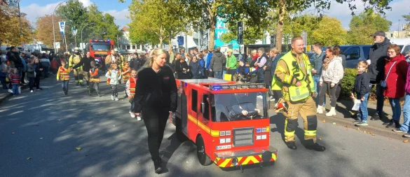Im Festzug: Das Mini-Feuerwehrauto steuern Leni und Phil, die Eltern Janine und Maik Menne sichern links und rechts ab. - © Dieter Scholz