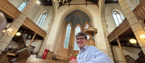 Tim Alexander sitzt in der Kilianskirche, im Hintergrund sieht man den Sternenhimmel im Altarraum. - © Sven Kienscherf