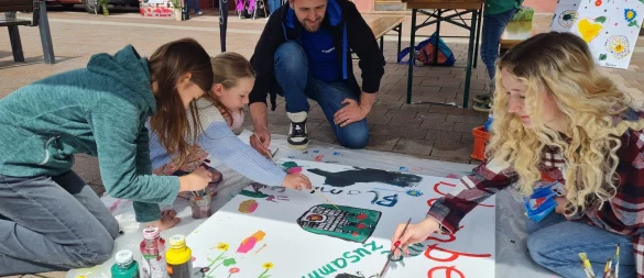 Junge Künstler auf dem Themenwochenmarkt zum Auftakt der Kunstmauer: Sozialpädagoge Sören Mellies (Mitte) und seine Kollegin Marleen Fürcht (rechts) freuen sich über die gute Resonanz. - © Marianne Schwarzer
