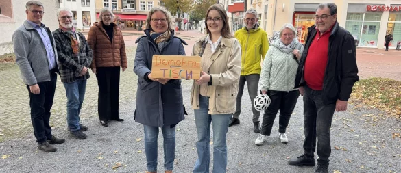 Michael Biermann, Helmut Behnisch, Pfarrerin Birgit Schneider, Ulrike Upmeyer, Benita Henning, Gerd Bicker, Christiane Dorß-Dierker sowie Manfred Hilbrink-Späth (von links) halten nicht nur symbolisch den "DemokraTisch", sondern grundsätzlich demokratische Werte hoch. - © Sandra Castrup