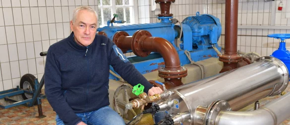 Wassermeister Olaf Frigge kniet im Pumpenhäuschen an der Schopke neben der Pumpe, in der das Wasser in dem Edelstahlrohr mit UV-Licht bestrahlt wird, um eventuell vorhandene Bakterien abzutöten. - © Gunter Held