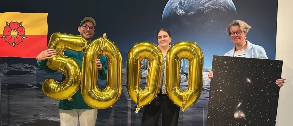 5000. Besucherin bei der Astronomie-Ausstellung im Weserrenaissance-Museum Schloss Brake: Museumsleiterin Silvia Herrmann (rechts) überreicht Celin Plener und Hayder Redzic aus Detmold eine von Klaus Eikmeier erstellte Fotografie aus dem Weltall. - © Alina Menkhoff