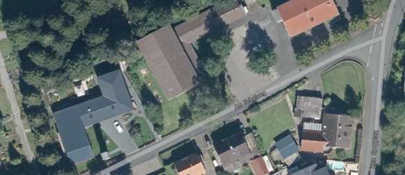 Die Straße "Am Schulweg" in Ahmsen aus der Vogelperspektive. Der neue Dorfplatz soll zwischen dem Dorfgemeinschaftshaus (rechts oben) und der Turnhalle (Bildmitte) entstehen. Hinter dem Dorfgemeinschaftshaus befindet sich weiterer Parkraum für Autos (ganz rechts). - © TIM-online/Geobasisdaten NRW