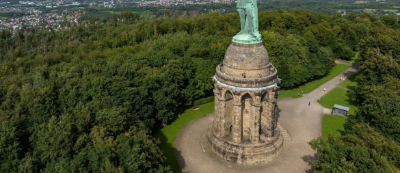 Blick auf das Hermannsdenkmal, Deutschlands größte Statue, in den Höhen des Teutoburger Waldes. Mehr als eine halbe Millionen Menschen besuchen den Ort jährlich. Am 16. August feiert der zuständige Landesverband Lippe den 150. Geburtstag des Hermannsdenkmals (Architektonische Höhe: 53 Meter) mit einem großen Familienfest. (Luftbild mit einer Drohne) (zu dpa: «Mythos und Geschichte: Das Hermannsdenkmal wird 150») - © Friso Gentsch/dpa