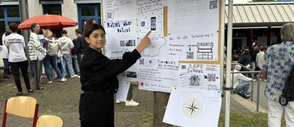 Siham Kako aus der 5a erklärt den "Rätsel-Parcours" beim Sommerfest. - © Jan Schillmann