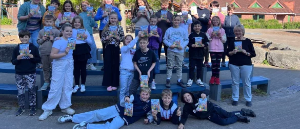 Die Schülerinnen und Schüler der Grundschule Nord haben von Buchhändlerin Martina Lange (rechts) das Buch bekommen. - © Grundschule Nord