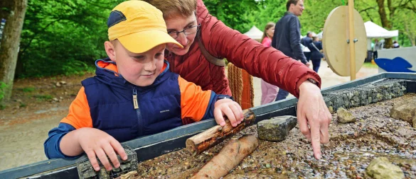 Theodor und Mama Sabrina gestalten am Stand des Projektes Wasser im Fluss den Wasserlauf in einem kleinen Flussbett. - © Nicole Ellerbrake