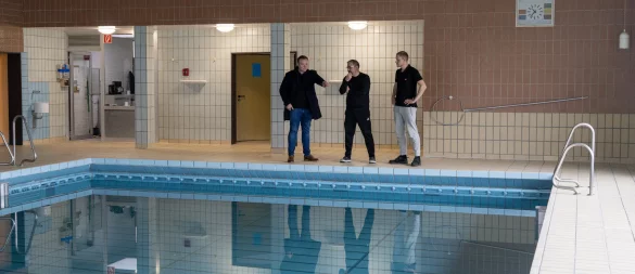 Bildunterschrift: Bürgermeister Michael Ruttner sowie Schwimmmeister Roberto Krierke und Philip Albert betrachten das Schwimmbecken der Schwimmhalle im Schulzentrum, das ab Montag wieder für Schulen und die Öffentlichkeit zur Verfügung steht. - © Bildrechte: Stadt Horn-Bad Meinberg
