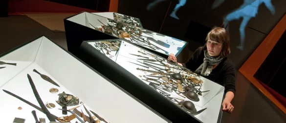 Unser Archivbild aus 2009 zeigt Ausstellungsmitarbeiterin Caroline Koch im Varusschlachtmuseum in Bramsche-Kalkriese (Landkreis Osnabrück). In der Vitrine sind Waffenopfer aus dem dänischen Illerup zu sehen. Das Museum widmet sich in seiner Sonderausstellung "Konflikt" den Kriegen in der germanischen Welt nach der Varusschlacht. Mehrere tausend archäologische Exponate aus ganz Europa sind für die Schau zusammengetragen worden. - © dpa