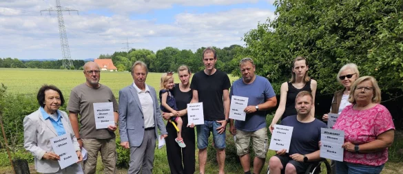 Ingrid Schmedding (von links), Ralf Mellies, Ferdinand Schmedding, Karina, Jan und Tabea Eke, Christian Dietz, Irina und Danilo Schmidt, Margarete Hilbrink und Martina Mellies stehen vor dem Feld, auf dem zwei große Windräder gebaut werden sollen. Sie protestieren dagegen und gründen eine Bürgerintiative. - © Astrid Sewing
