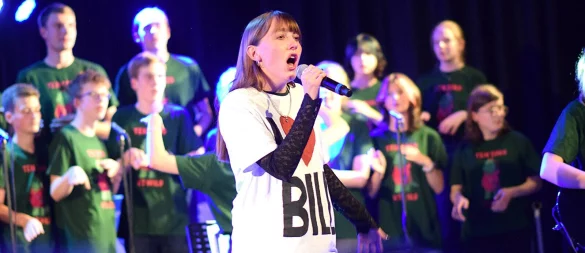 Während der Show treten immer wieder Solistinnen und Solisten auf. Im Hintergrund begleitet der Chor in den zum Abend passenden grünen Shirts die Auftritte. - © Karin Prignitz
