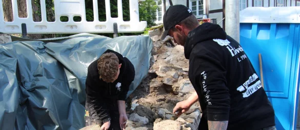 Jannes Klemme (links) und Kevin Kickert bauen die Bruchsteinmauer an der Herforder Straße wieder auf. - © Nadine Uphoff