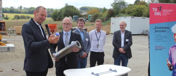 Hochschulpräsident Professor Dr. Jürgen Krahl (von links) bestückt die Zeitkapsel mit einem Kraftstoff, der die Bezeichnung "RS 75" trägt. Auch Projektleiter Professor Dr. Thomas Schulte, Martin Griese, Timo Broeker und Professor Dr. Holger Borcherding haben die Kapsel bei der Grundsteinlegung fürs "Mobilitätszentrum UrbanLand" an der TH OWL in Lemgo bereits gefüllt. In dem Gebäude soll auch an E-Fuels geforscht werden. - © Jens Rademacher