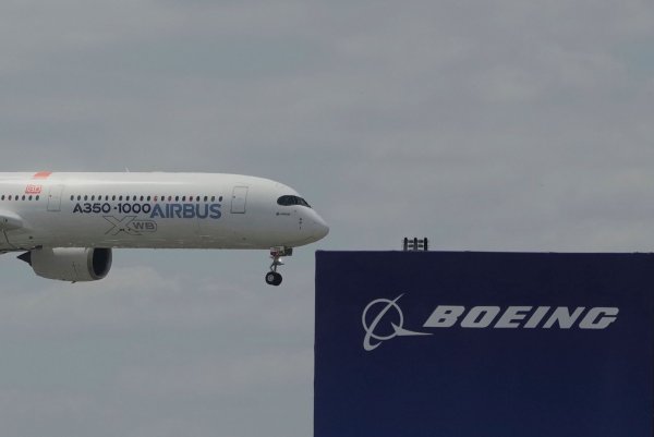 Die zwei großen Konkurrenten: Ein Airbus fliegt bei einer Vorführung auf der Luftfahrtmesse Salon du Bourget an einem Logo von Boeing vorbei. - © Michel Euler/AP/dpa