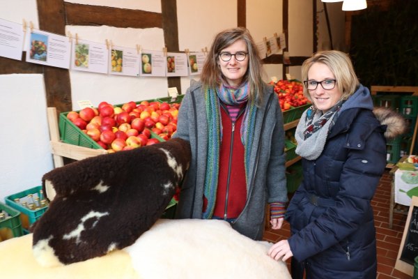 Alles selbst gemacht: Ellen Siegismund-Kuhlmann (links) zeigt  Kundin Anneke Wolff ein Schafsfell. Dahinter stehen die Apfelkisten. - © Guntmar Wolff