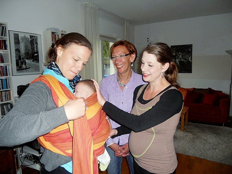 Gut gebunden, gute Bindung: Katja Schüsser (rechts) demonstriert an Friederike Müller mit einer Puppe, wie das Tragetuch eingesetzt wird. Andrea Tilmanns-Bittel schaut zu. - © Foto: Köhring