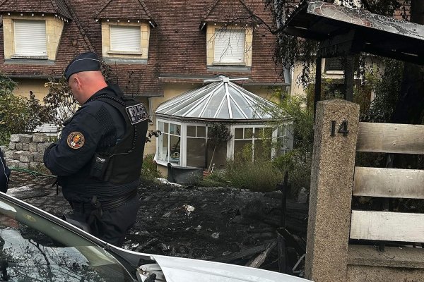 Ein Polizist steht vor dem Haus des Bürgermeisters Vincent Jeanbrun. Randalierer hatten das Haus in der Nacht mit einem Auto gerammt und Feuer gelegt. - © Nassim Gomri/AFP/dpa