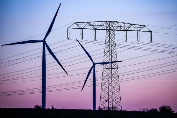Windkraftanlagen und Hochspannungsleitungen sind vor dem Abendhimmel bei Leuna zu sehen. - © Jan Woitas/dpa