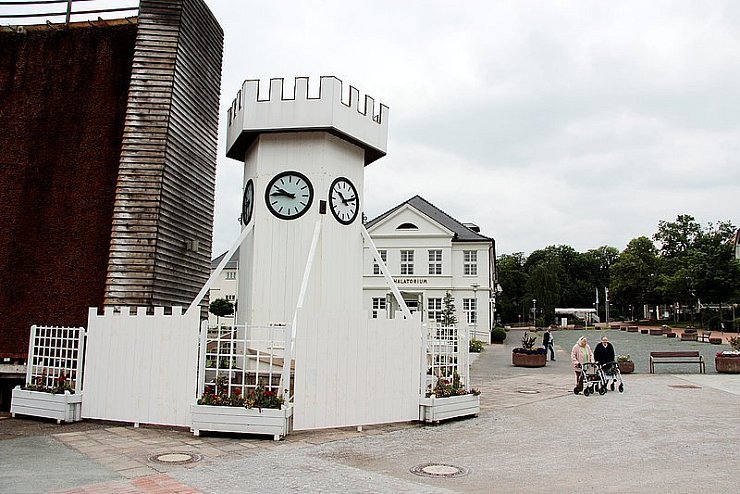 Der Original-Uhrenturm ist vor der Demontage des Salinenpark-Gradierwerks gerettet worden. Der Bauhof hat ihn nun mit einem adäquaten Sichtschutz versehen. Der graue Kies (rechts) verrät den alten Standort des Gradierwerks. - © Foto: Backe