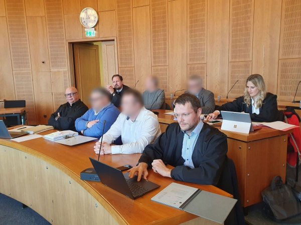 Die vier Angeklagte sitzen mit ihren Verteidigern im Gerichtssaal im Landgericht. - © Martin Höke/dpa