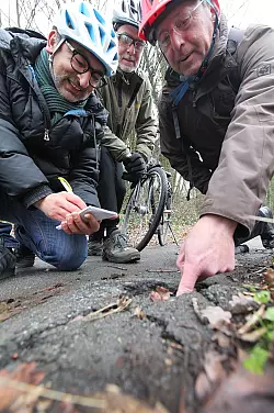 Frank Loke, Werner Kloppmann und LZ-Redakteur Erol Kamisli (von links) nehmen den aufgerissenen Asphalt auf dem Radweg an der Rintelner Straße unter die Lupe. - © Vera Gerstendorf-Welle