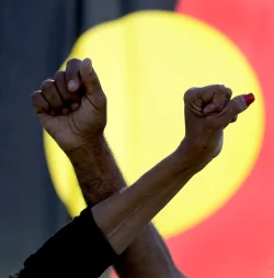 Ein Mann und eine Frau verschr&auml;nken die Arme vor einer Aborigines-Flagge w&auml;hrend einer Kundgebung der Bewegung &laquo;Black Lives Matter&raquo; in Sydney (Symbolbild). Der &laquo;Sydney Morning Herald&raquo; hat sich f&uuml;r seine Berichterstattung zum Myall-Creek-Massaker entschuldigt. - &copy; Rick Rycroft/AP/dpa