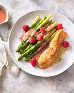 Für dieses Gericht werden grüne Spargelstangen bissfest gebraten und mit Himbeeren kombiniert - raffiniert, aber rasch zubereitet. - © Hubertus Schüler/Becker Joest Volk Verlag/dpa-tmn