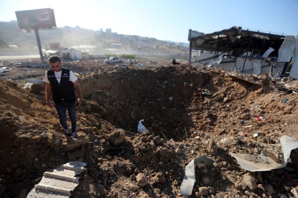 Ein libanesischer Polizist steht in der Nähe eines Kraters nach einem israelischen Luftangriff auf einen Hangar im Südlibanon. - © Mohammed Zaatari/AP/dpa