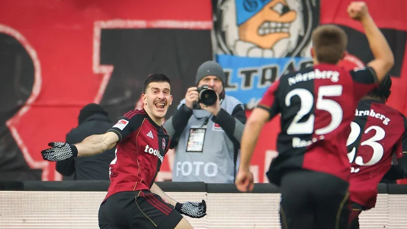 Luka Lotschoschwili (l) bejubelt sein erstes Tor für Nürnberg. - © Daniel Karmann/dpa