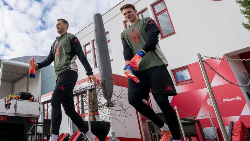 Torwart Manuel Neuer (l) und Ersatzkeeper Jonas Urbig auf dem Weg auf den Trainingsplatz. - &copy; Peter Kneffel/dpa