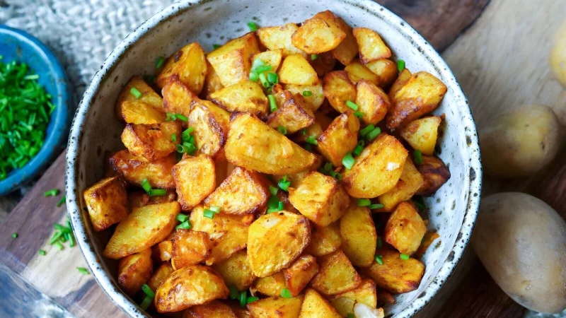 Nur kleine Mengen Fett bekommen Bratkartoffeln per Ölsprüher ab, werden mit Salz und Paprikapulver gewürzt und kommen in den Airfryer: Nach 25 Minuten sind die Kartoffelstücke richtig schön knusprig. - © Steffi Sinzenich/gaumenfreundin.de/dpa-tmn