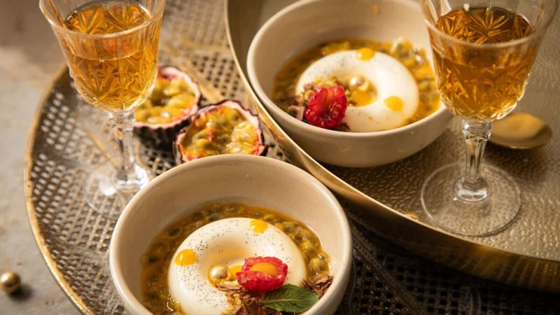 Panna Cotta mit Passionsfrucht, Himbeere, Mangotupfer, Minze, Pistazie, Schokolade und goldenen Schokokugeln in Savarin-Form zubereitet. Das ist eine Backform in flacher, ringf&ouml;rmiger Gestalt. - &copy; Christin Klose/dpa-tmn