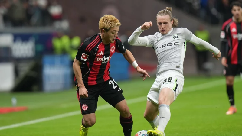 Lieferten sich eine umkämpfte Partie: Eintracht Frankfurt um Ritsu Doan (l) und der VfL Wolfsburg um Patrick Wimmer (r). - © Thomas Frey/dpa