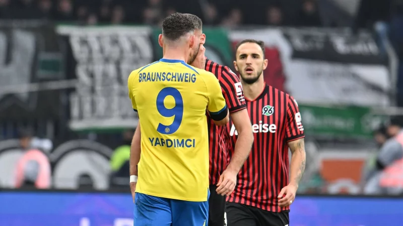 Erencan Yardimci von Eintracht Braunschweig fasst seinem Gegenspieler Boris Tomiak beim Derby gegen Hannover 96 mit beiden H&auml;nden an den Hals. - &copy; Swen Pf&ouml;rtner/dpa