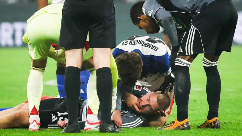 HSV-Verteidiger Luka Vuskovic hilft dem am Boden liegenden Eintracht-Profi Rasmus Kristensen. - &copy; Christian Charisius/dpa