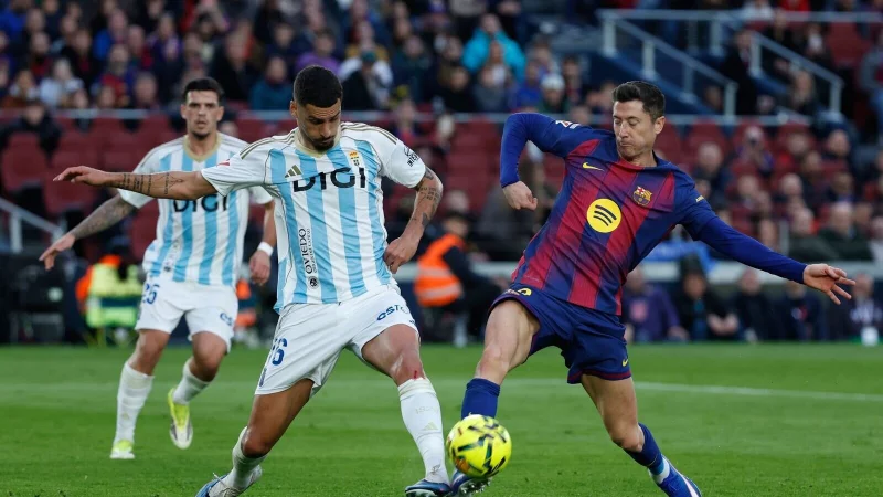 Barcelonas Robert Lewandowski (r) im Zweikampf mit David Carmo von Real Oviedo. - &copy; Joan Monfort/AP/dpa