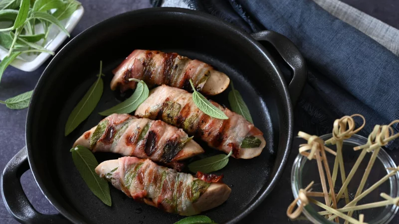 Ob in der Pfanne oder auf dem Grill: Umwickelt mit Salbeiblättern und Speck werden die Saltimbocca-Bratwürstchen garantiert zum Highlight. - © Julia Uehren/loeffelgenuss.de/dpa-tmn