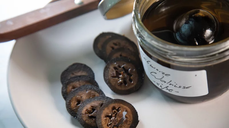 Fr&uuml;hstens an Weihnachten werden die in Gew&uuml;rzsirup eingelegten schwarzen Waln&uuml;sse aufgeschnitten und werden als feines Topping f&uuml;r Eis oder K&auml;se genutzt. - &copy; Christin Klose/dpa-tmn