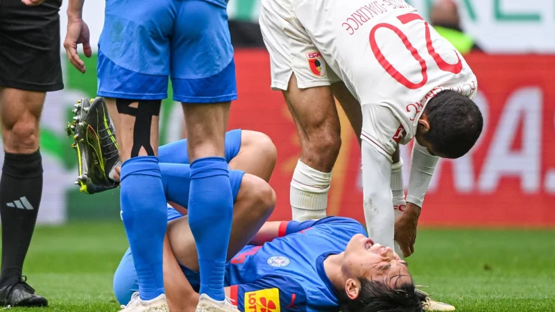 Das Aus für Shuto Machino: Der Kieler Angreifer liegt in Augsburg verletzt am Boden. - © Armin Weigel/dpa