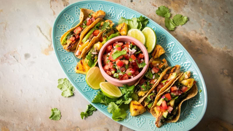 Richtig stilecht werden H&auml;hnchen-Tacos erst mit Zugaben wie der mexikanische Tomatensalsa &laquo;Pico de Gallo&raquo;, argentinischer Kr&auml;utersauce &laquo;Chimichurri&raquo;, Avocado, gegrillter Ananas, Koriander und Limetten. - &copy; Christin Klose/dpa-tmn