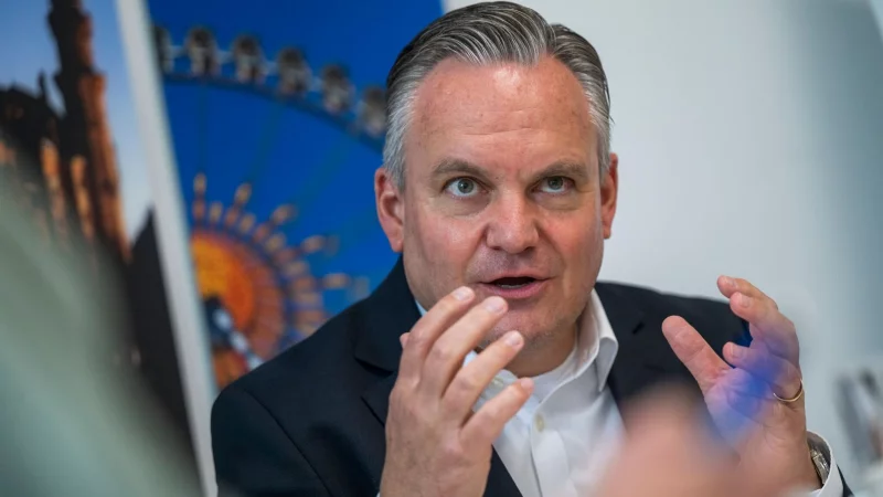 Münches neuer Wiesnchef Scharpf vor einem Foto des Riesenrades. - © Peter Kneffel/dpa