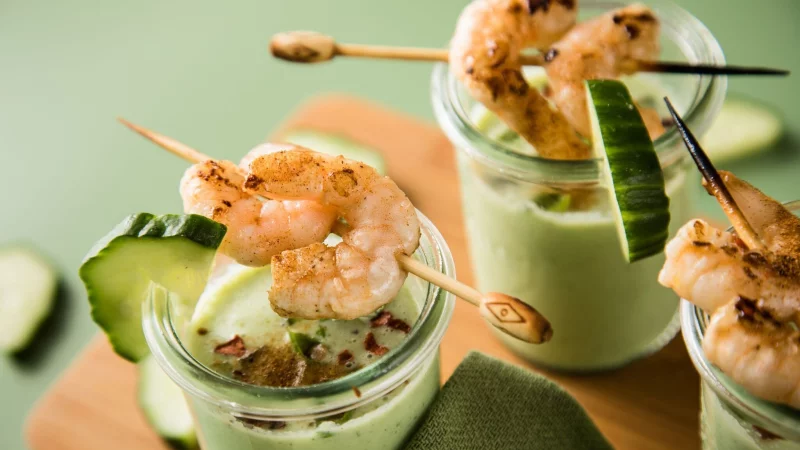 Eine kalte Suppe erfrischt an warmen Tagen - wie diese aus Gurken, Buttermilch und Basilikum, getoppt mit Garnelenspießen, Chiliflocken und Cayennepfeffer. - © Christin Klose/dpa-tmn