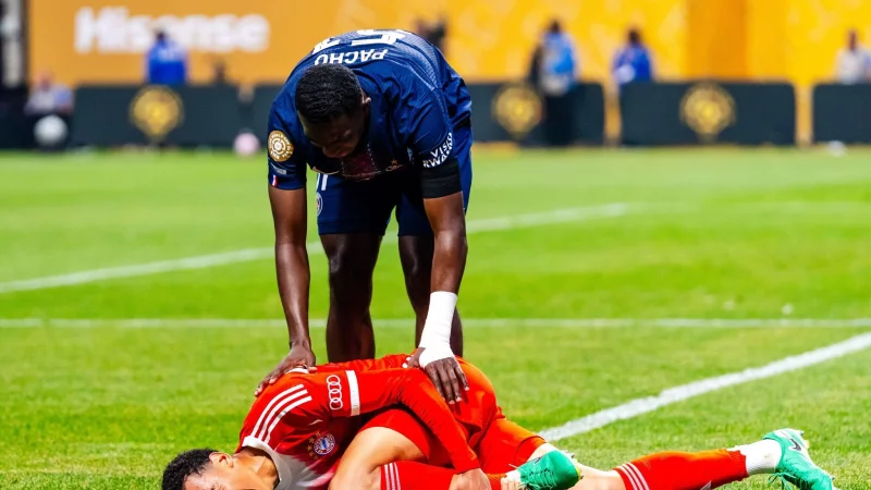 Jamal Musiala liegt mit starken Schmerzen verletzt am Boden. PSG-Profi William Pacho kümmert sich um ihn. - © Malachi Gabriel/ZUMA Press Wire/dpa