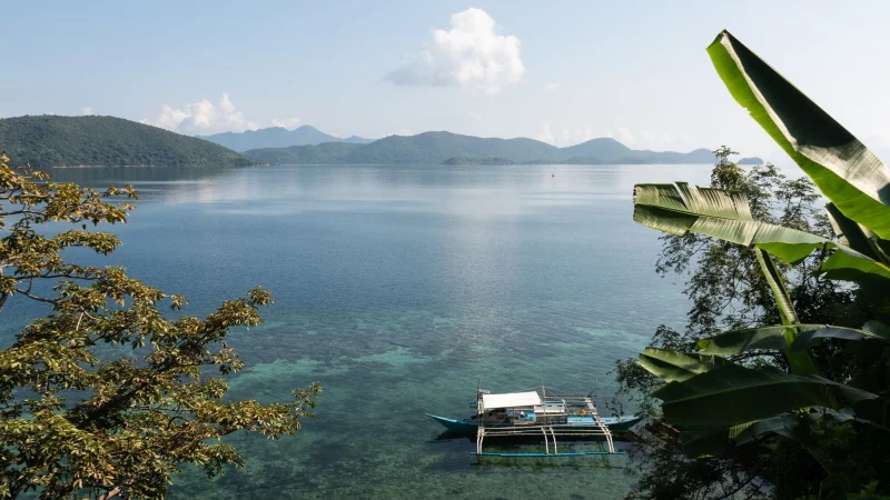 Im Wasser schaukelt ein Auslegerboot, eine Brise raschelt in den Palmblättern: So sieht ein verlorenes Inselparadies aus. - © Andreas Drouve/dpa-tmn